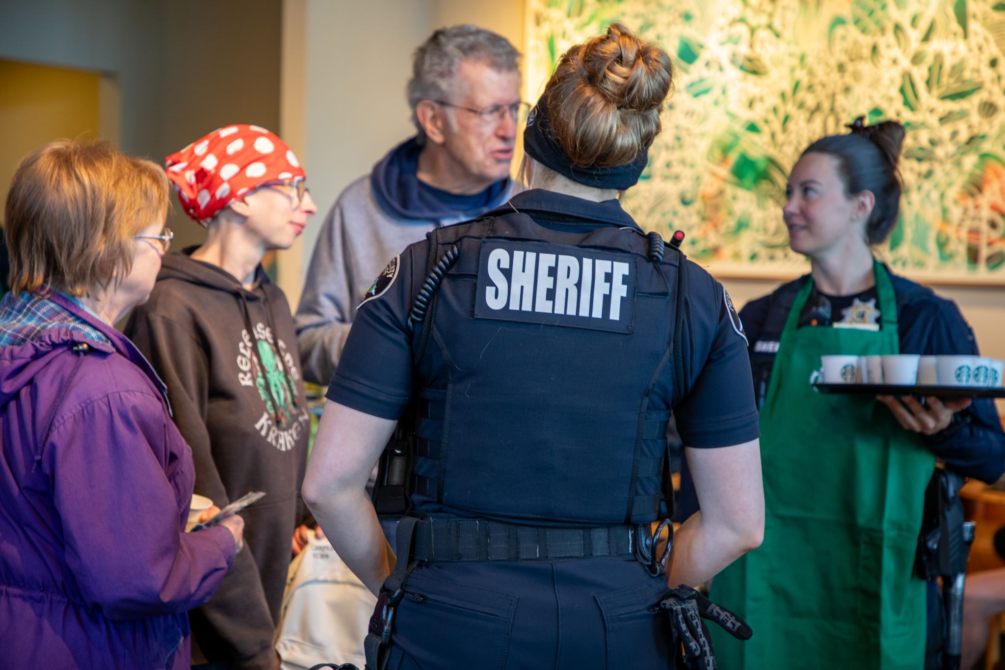 Two police officers standing with group of people talking inside coffee shop