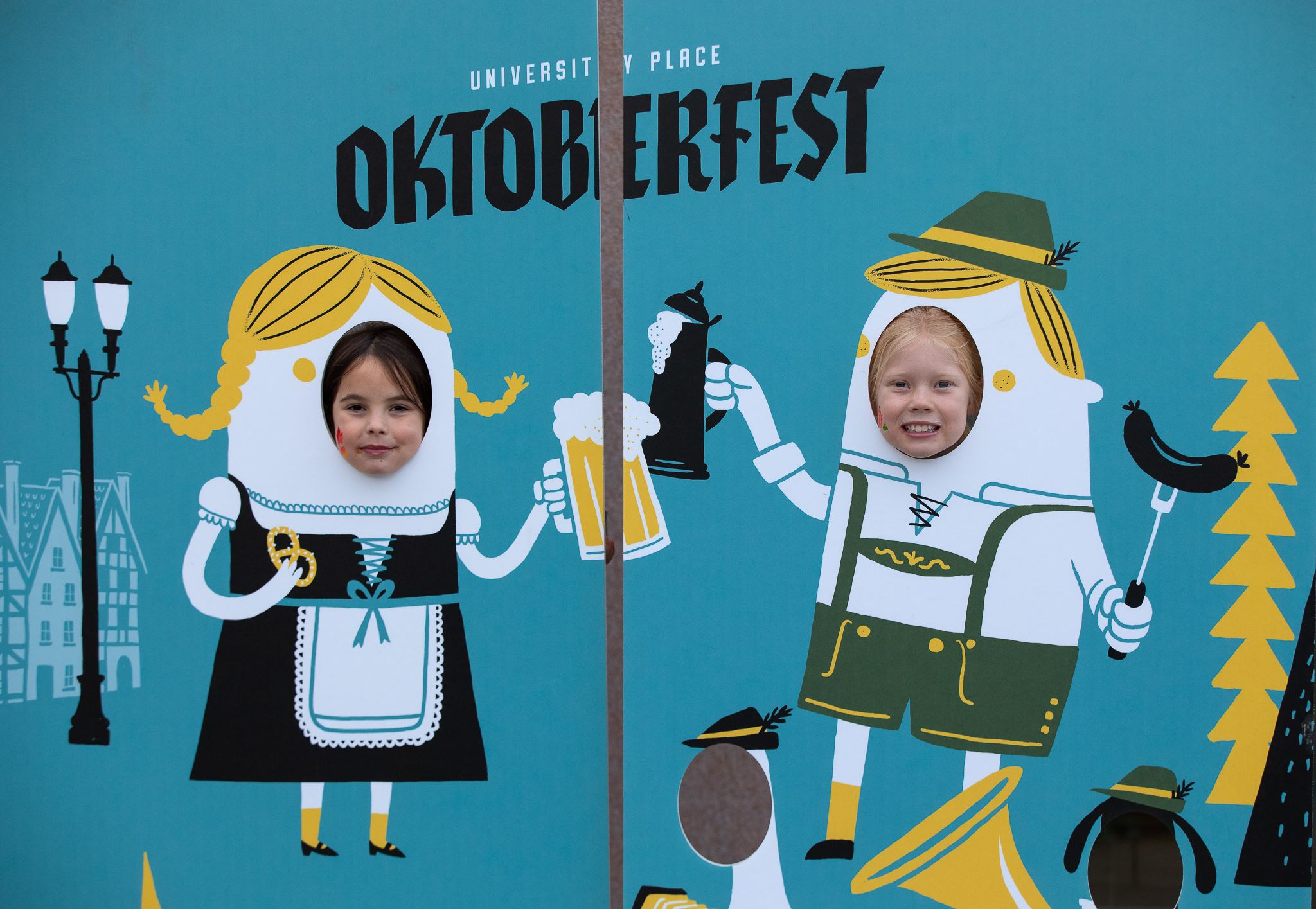two children standing behind a photo wall with holes in it